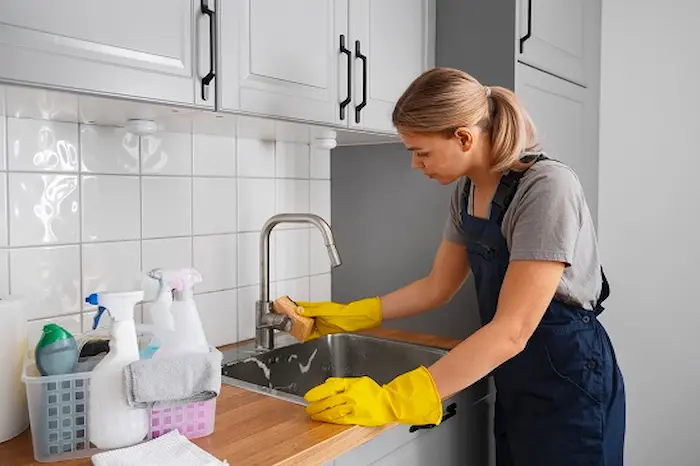 خانم خانه دار در حال تمیز کردن چربی و روغن روی سینک ظرفشویی برای جلوگیری از بوی بد سینک ظرفشویی 48545